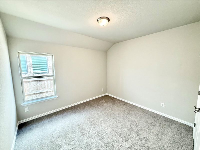 Empty room with lofted ceiling, carpet, and a textured ceiling Empty room with lofted ceiling, carpet, and a textured ceiling