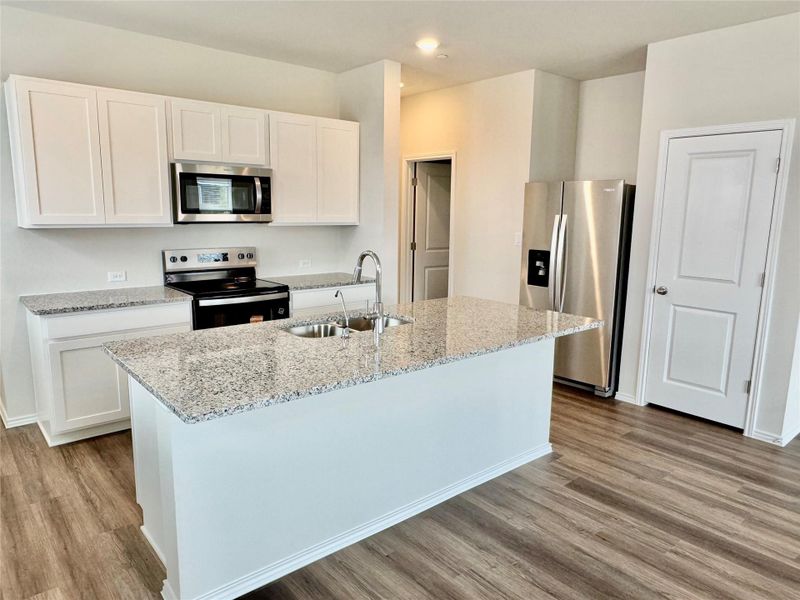 Kitchen with appliances with stainless steel finishes, white cabinetry, and a kitchen island with sink