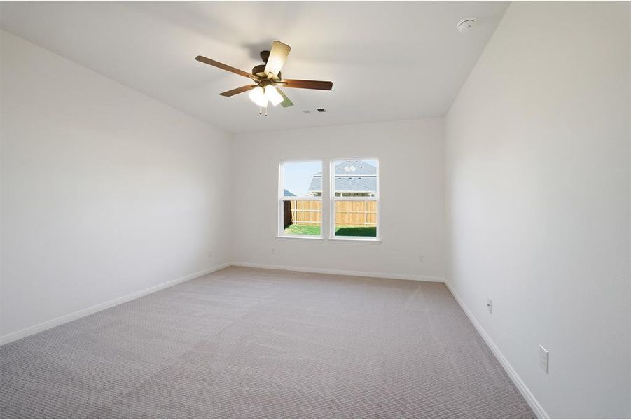 Carpeted interior room featuring a ceiling fan with integrated lighting, two windows, and white baseboards
