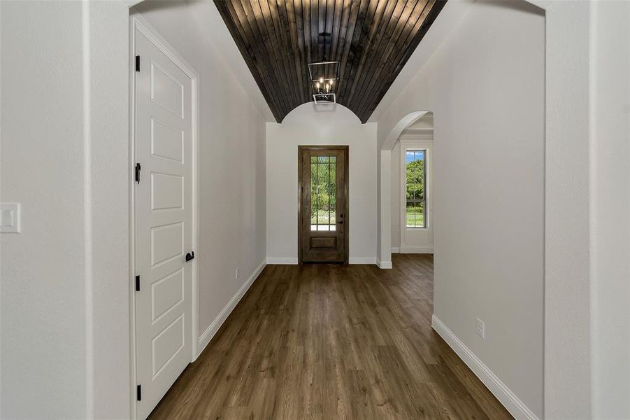 Entrance foyer with dark wood finished floors, lofted ceiling, a chandelier, and arched walkways