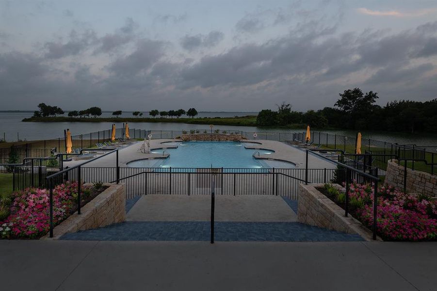 Multi-level swimming pool with integrated seating surrounded by a black metal fence Multi-level swimming pool with integrated seating surrounded by a black metal fence