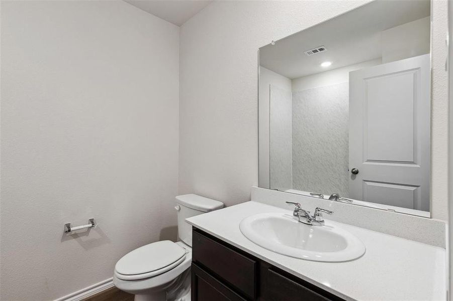 Bathroom featuring a dark wood-finish vanity with a white countertop, an oval undermount sink, and a chrome faucet