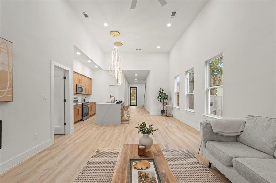 Living room featuring recessed lighting, a towering ceiling, light wood finished floors, baseboards, and ceiling fan Living room featuring recessed lighting, a towering ceiling, light wood finished floors, baseboards, and ceiling fan