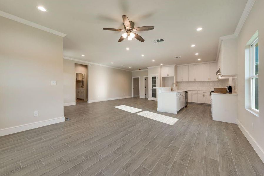 Unfurnished living room with plenty of natural light, ornamental molding, and ceiling fan