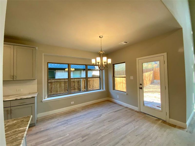 Breatfast area with window seat, lots of window, and Brushed Nickel chandelier. Opens to covered patio