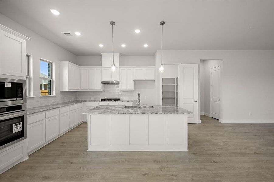 Kitchen with stainless steel appliances, white cabinets, backsplash, a center island with sink, and recessed lighting Kitchen with stainless steel appliances, white cabinets, backsplash, a center island with sink, and recessed lighting