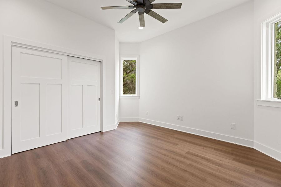 Unfurnished bedroom featuring dark wood-style floors, multiple windows, and baseboards Unfurnished bedroom featuring dark wood-style floors, multiple windows, and baseboards