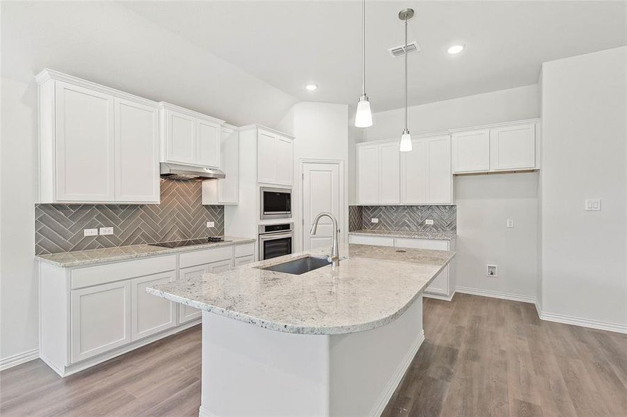 Kitchen featuring white cabinetry, wall chimney range hood, light wood-type flooring, appliances with stainless steel finishes, and backsplash