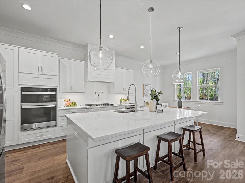 Stunning chef’s kitchen featuring a large center island, quartz countertops, stainless steel appliances, custom cabinetry, and modern pendant lighting—perfect for cooking and entertaining.