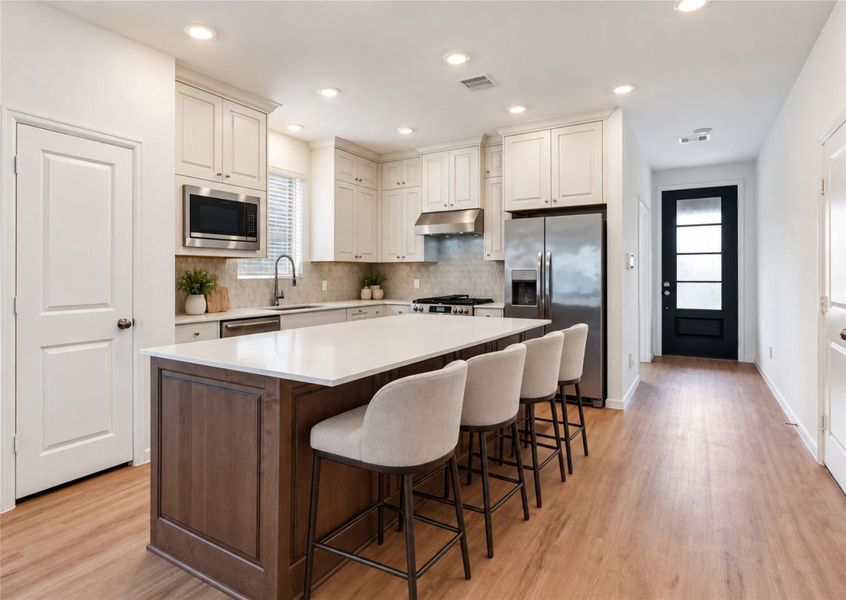 Beautiful two-toned luxury kitchen with upgraded raised panel cabinetry and stone backsplash! Sink window and recessed lighting flood this room with light, while the quartz countertops, gas range, stainless steel appliances, and large pantry offer function and beauty!
