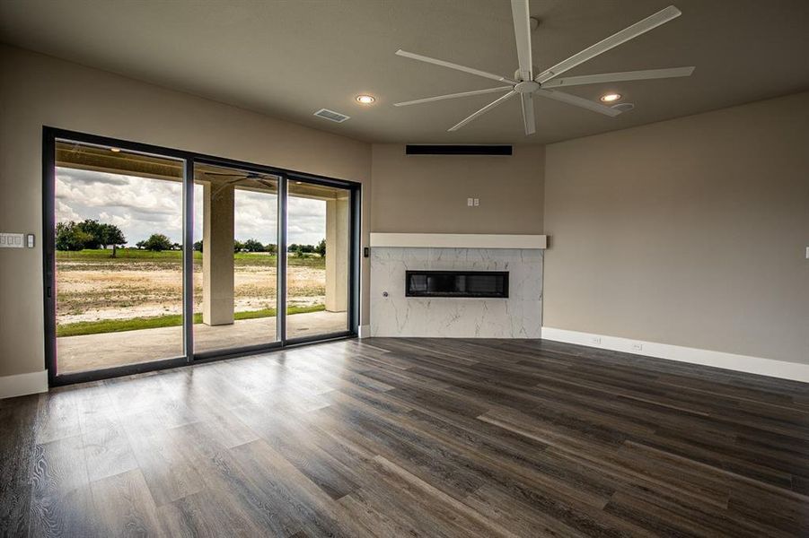 Open concept living room with ceiling fan, gas fireplace and sliding glass door out to patio with ceiling fans and outdoor speakers