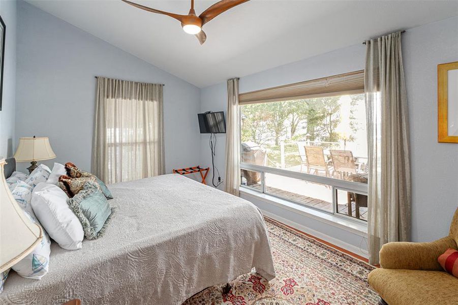 Vaulted ceiling bedroom with a contemporary ceiling fan, illuminated by a large picture window and an additional vertical window