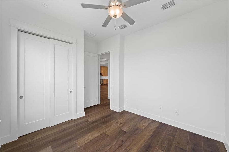 Room featuring wood-finish flooring, a ceiling fan with integrated lighting, recessed lighting, and a closet with sliding panel doors