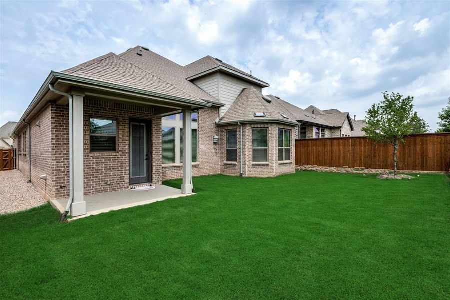 Rear view of property with brick siding, roof with shingles, and a patio