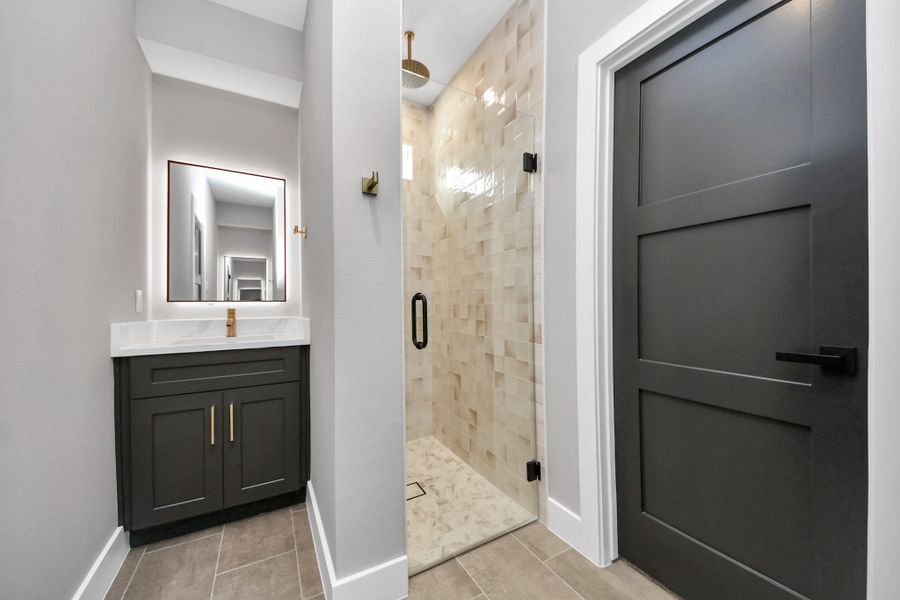 Spa-like primary bathroom featuring modern finishes, a sleek walk-in shower with designer tile, LED mirror lighting, and separate vanities for added comfort and convenience.