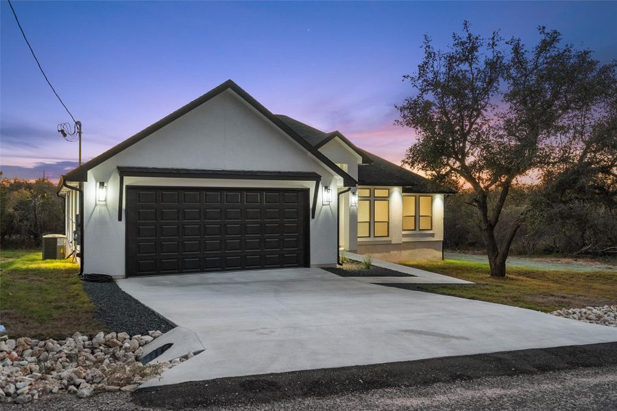 Ranch-style home with concrete driveway, stucco siding, and a garage