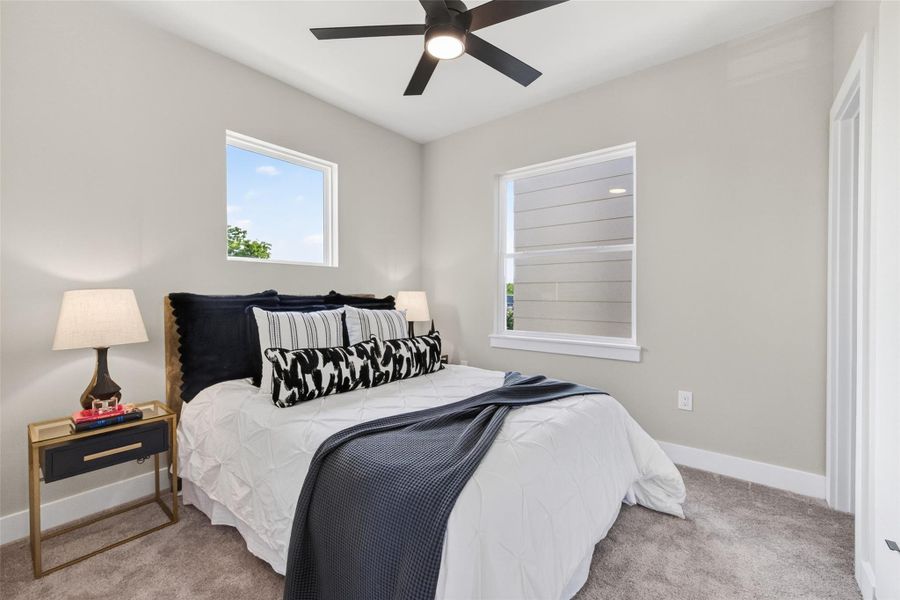 The third-floor secondary bedroom is a bright, well-proportioned room with plush carpet, a ceiling fan, two windows, and en suite full bath. Sharing the third floor with the primary bedroom, it makes an ideal second bedroom or office.