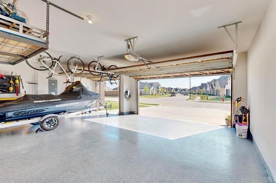 3-car garage with electric panel, a garage door opener, and a residential view