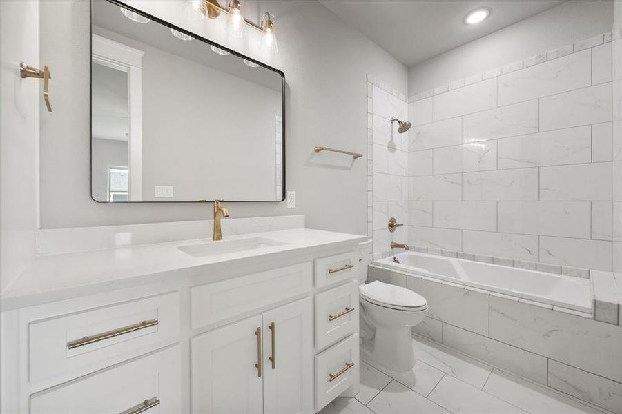 Modern bathroom featuring a white vanity with gold-finish hardware, a rectangular undermount sink, and a large black-framed mirror