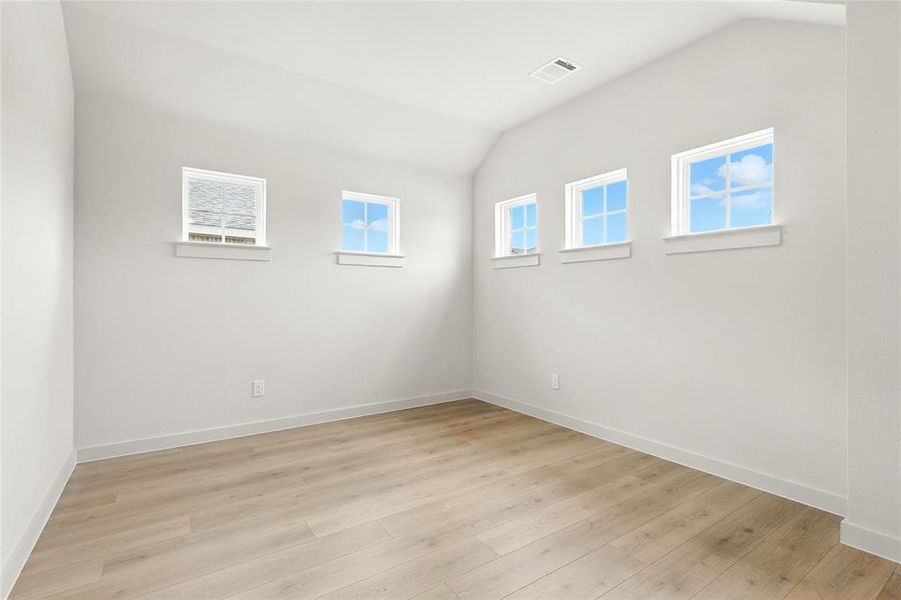 Empty room featuring lofted ceiling and light wood-style floors