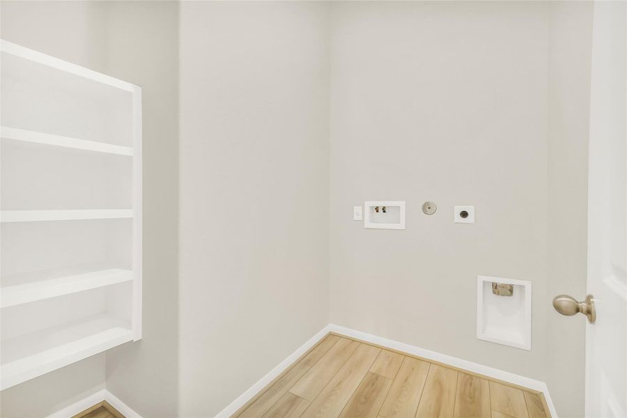 The functional utility room is equipped with built-in shelving and organized space to handle household tasks with ease.