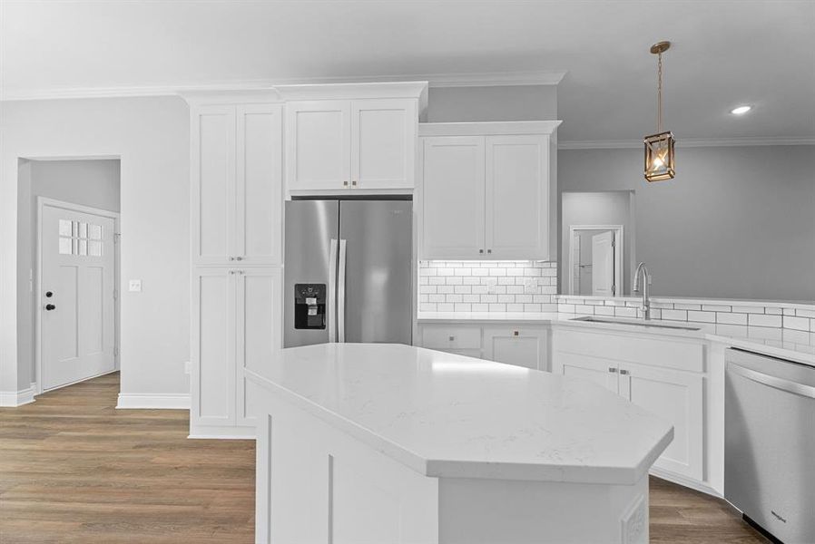 Kitchen featuring stainless steel appliances, tasteful backsplash, white cabinetry, light stone countertops, and decorative light fixtures