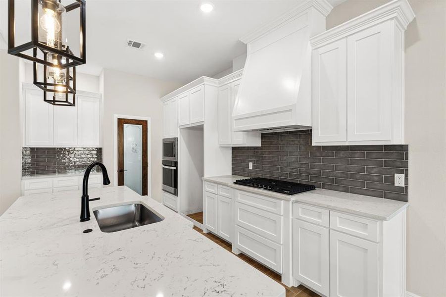 Kitchen featuring light stone countertops, white cabinetry, tasteful backsplash, hanging light fixtures, and recessed lighting