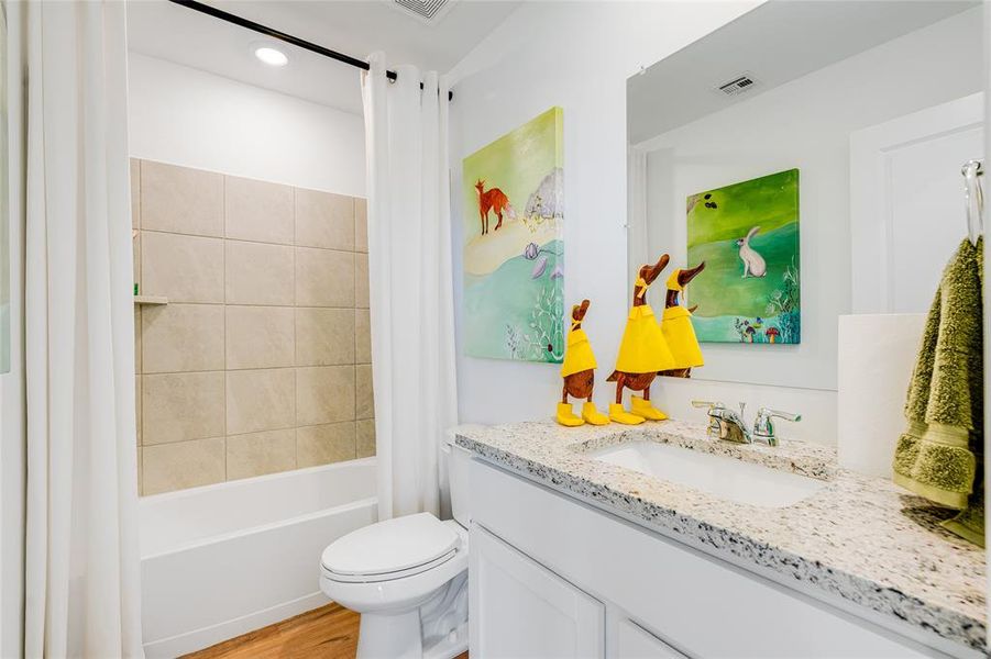 Full bathroom featuring hardwood / wood-style floors, shower / bath combo, vanity, and toilet