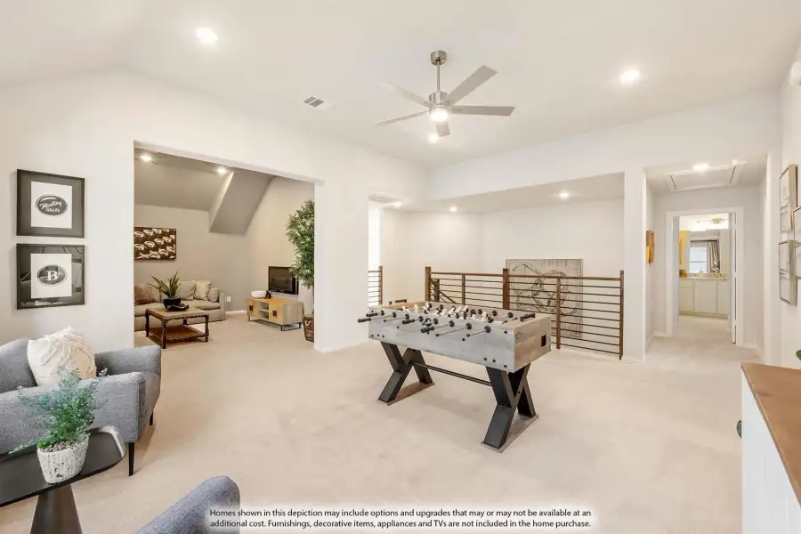 Upstairs game room with foosball table, ceiling fan, carpet flooring, and open staircase railing