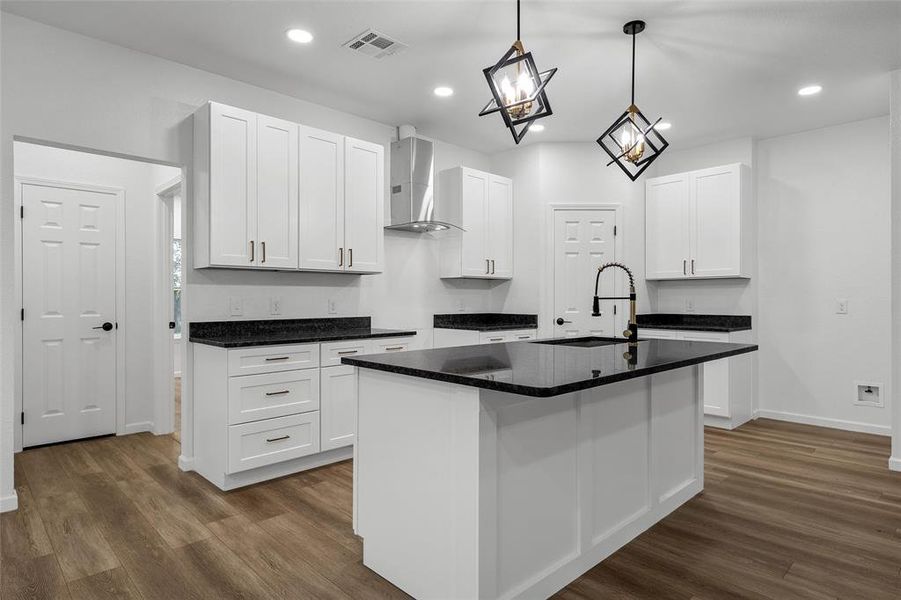 Modern kitchen featuring white cabinetry, dark countertops, and wood-finish flooring Modern kitchen featuring white cabinetry, dark countertops, and wood-finish flooring