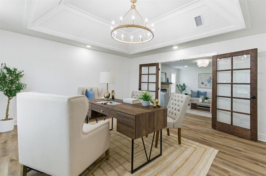 This room features a tray ceiling with a chandelier, recessed lighting, and light wood flooring This room features a tray ceiling with a chandelier, recessed lighting, and light wood flooring