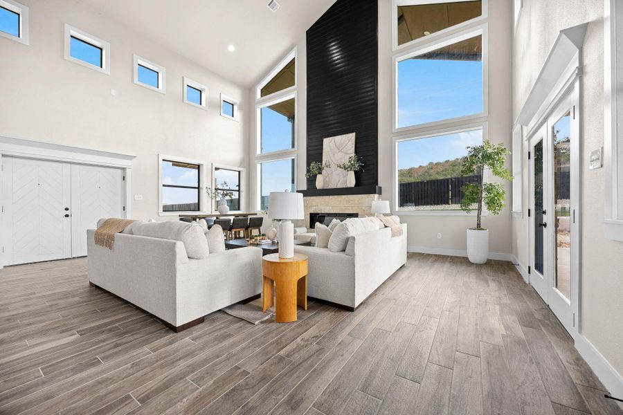 Living room with a fireplace, light wood-type flooring, and a towering ceiling Living room with a fireplace, light wood-type flooring, and a towering ceiling