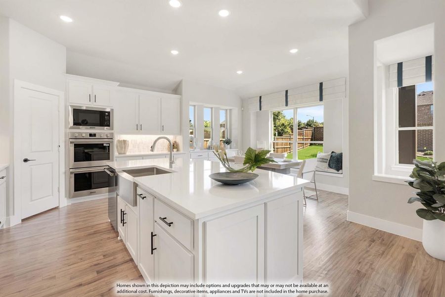 Open kitchen with white cabinets, center island, stainless steel appliances, and hardwood floors overlooking a dining area with backyard views.