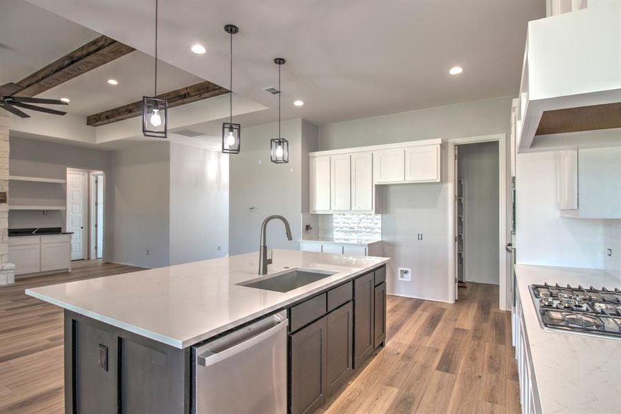 Kitchen with a center island with sink, appliances with stainless steel finishes, white cabinetry, wood-type flooring, and sink