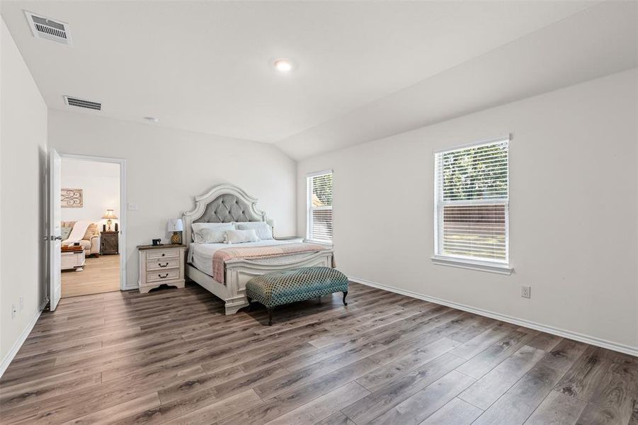 Expansive primary suite with oversized windows, natural light, and luxury vinyl plank flooring. Expansive primary suite with oversized windows, natural light, and luxury vinyl plank flooring.