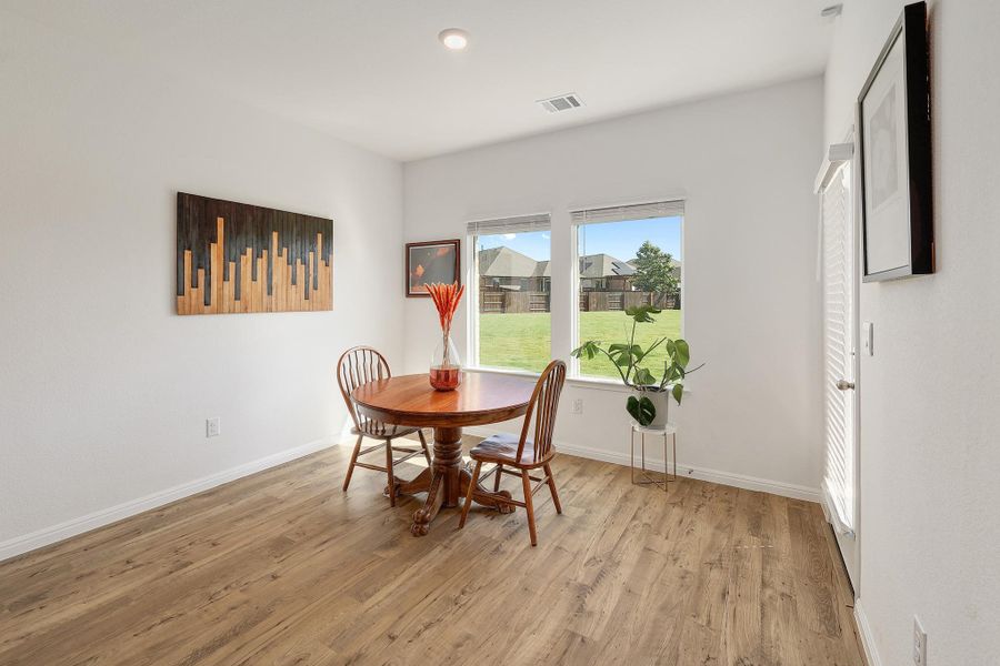 Room with wood-finish flooring, white baseboards, and white walls Room with wood-finish flooring, white baseboards, and white walls