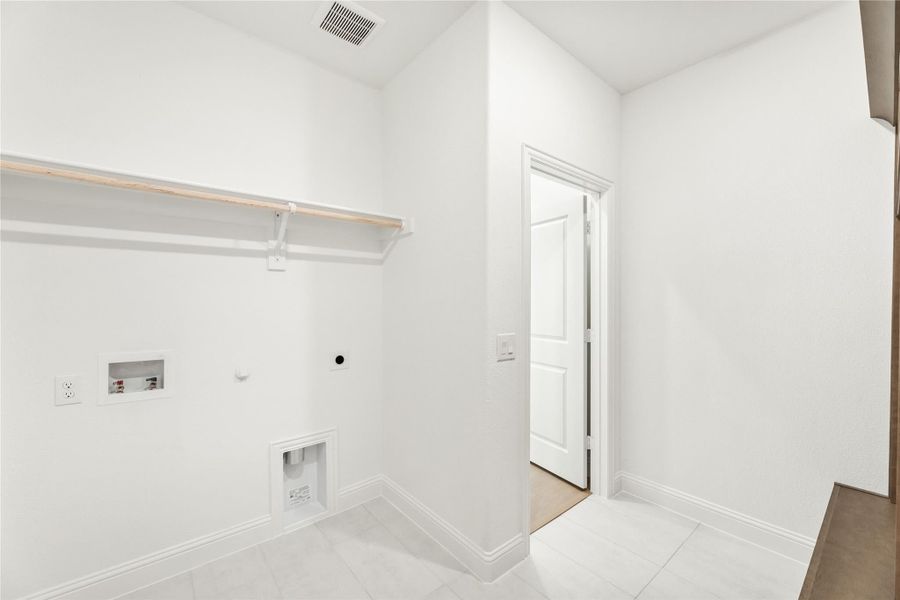 Empty laundry room with wall shelf, washer and dryer hookups, and tile floor Empty laundry room with wall shelf, washer and dryer hookups, and tile floor