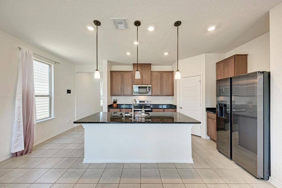 A well-appointed culinary space featuring sleek black countertops and an inviting island for meal prep and casual dining.
