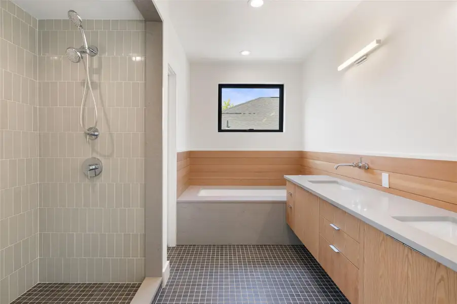 Full bathroom with a stall shower, double vanity, dark tile patterned floors, a garden tub, and recessed lighting Full bathroom with a stall shower, double vanity, dark tile patterned floors, a garden tub, and recessed lighting