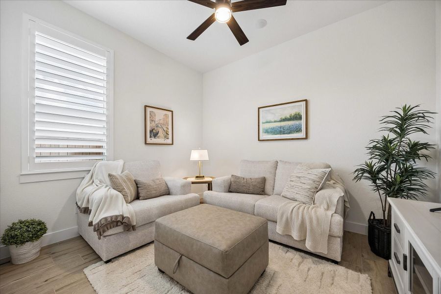 The second bedroom features custom plantation shutters, wood-plank tile flooring, and a ceiling fan. This versatile space is ideal as a guest room, children’s bedroom, hobby room, or entertainment area, as shown.