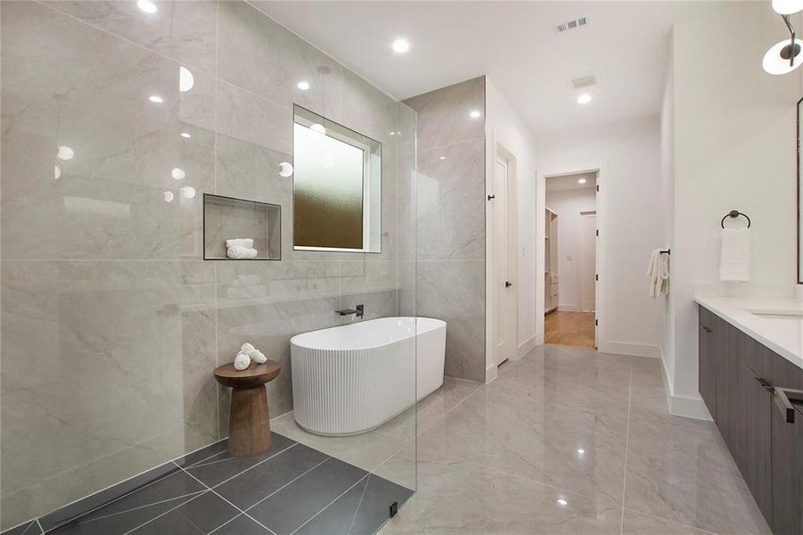 Bathroom featuring tile walls, vanity, a freestanding tub, marble tiled floors, and baseboards Bathroom featuring tile walls, vanity, a freestanding tub, marble tiled floors, and baseboards