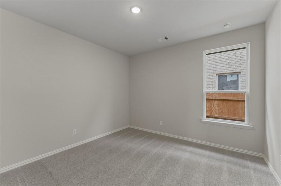 Neutral tone walls, recessed lighting, white trim, grey carpeting, and a white-framed window