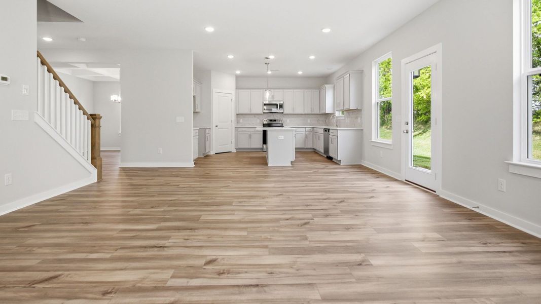 First floor with hard surface flooring, windows, nearby staircase, and view into the kitchen First floor with hard surface flooring, windows, nearby staircase, and view into the kitchen