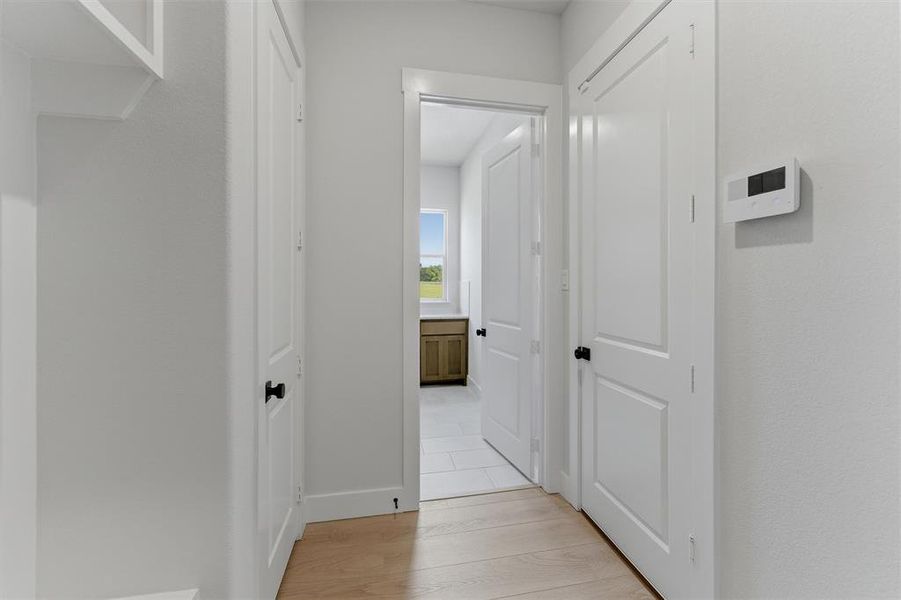 Bright hallway featuring light wood-finish flooring and crisp white walls