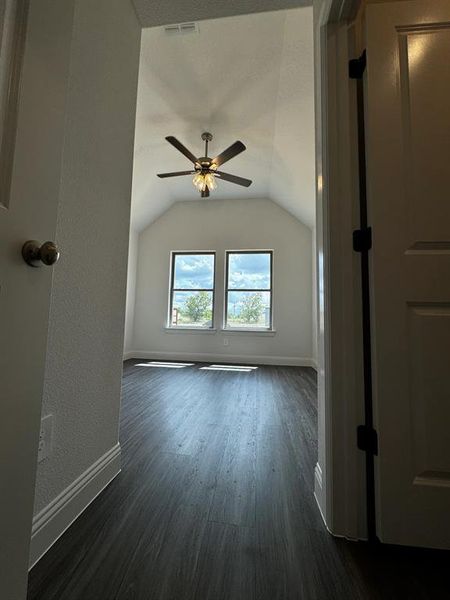 Additional living space with ceiling fan, dark hardwood / wood-style flooring, and lofted ceiling