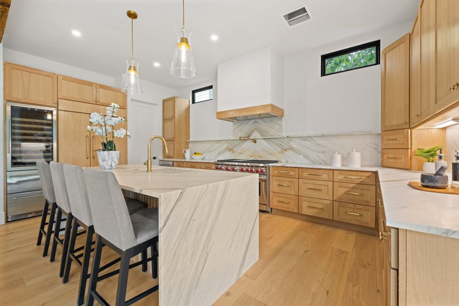 Warm wood cabinetry and bookmatched stone surfaces define this gourmet culinary space.