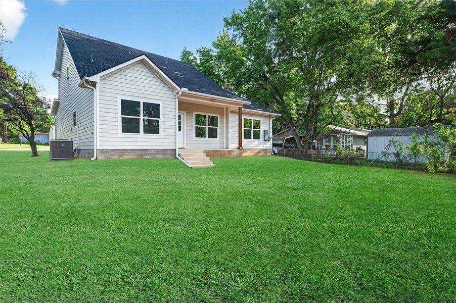 Back of house featuring a yard, a shingled roof, and entry steps Back of house featuring a yard, a shingled roof, and entry steps