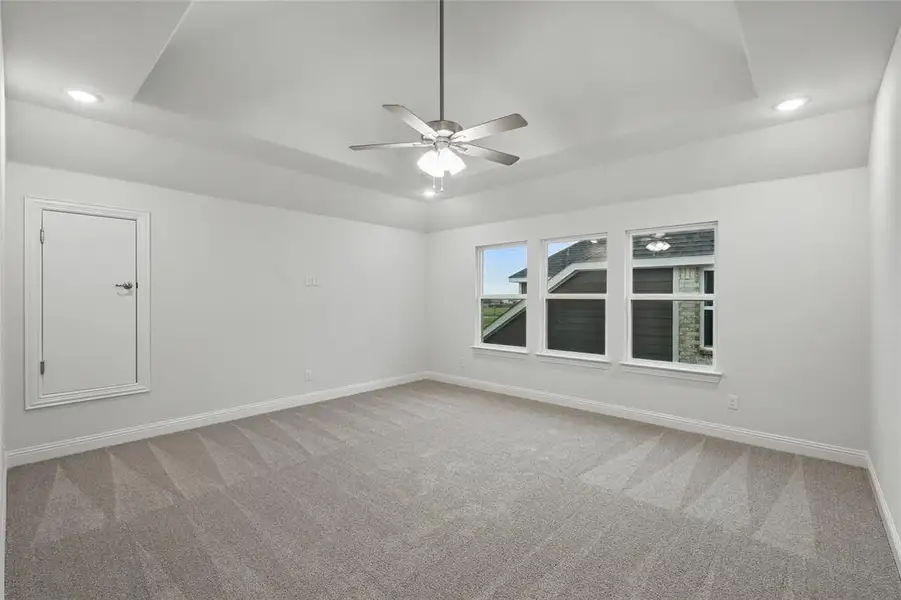 Carpeted empty room featuring a ceiling fan, baseboards, recessed lighting, and a raised ceiling