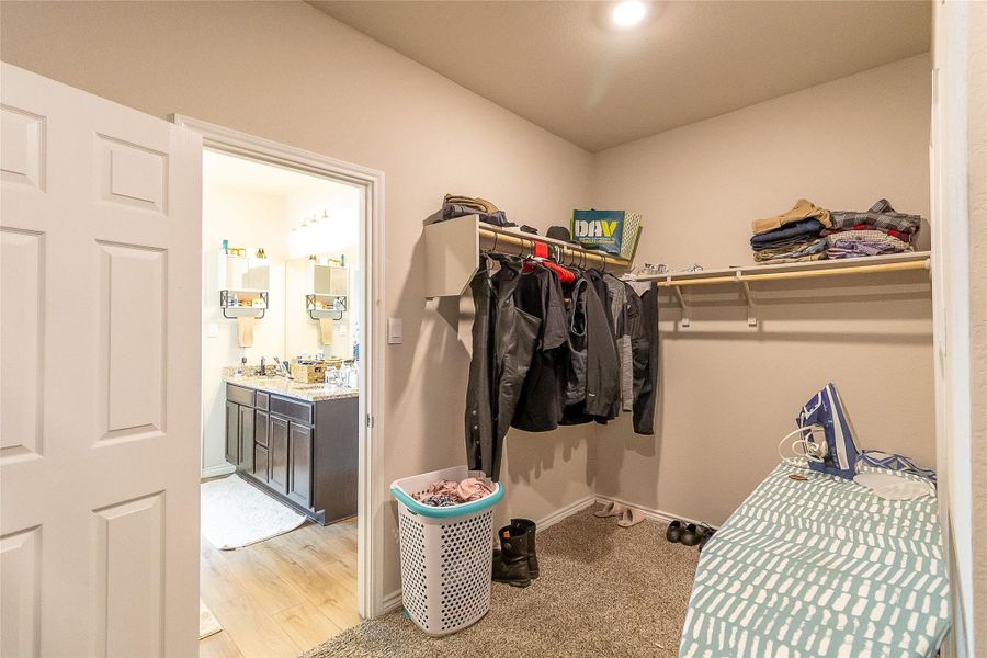 A well-organized walk-in closet offers ample storage adjacent to a bright, modern bathroom.