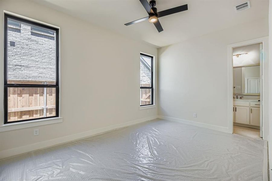 Unfurnished bedroom with light carpet, connected bathroom, and ceiling fan